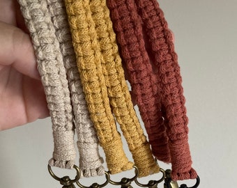 May include: Four crocheted keychains in beige, yellow, and red with gold and black metal clasps.