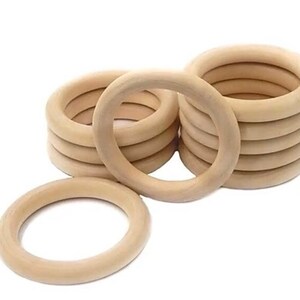 May include: A stack of 10 unfinished wooden rings, each with a diameter of approximately 3 inches. The rings are made of natural wood and have a smooth, polished finish.