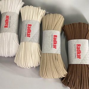 Puede incluir: Cuatro carretes de cordón de costura en blanco, beige, marrón y marrón oscuro. Cada carrete tiene una etiqueta que dice "Radkar Sewing Cord".