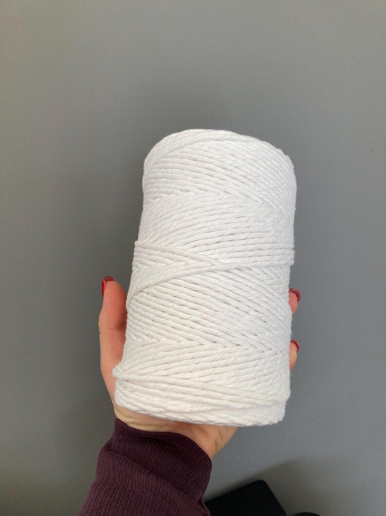 K&ouml;nnte beinhalten: Ein Kn&auml;uel aus wei&szlig;em Baumwollseil, fest gewickelt, wird in einer Hand gehalten. Das Seil ist dick und hat eine nat&uuml;rliche Textur.