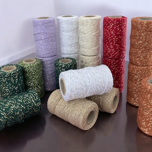 Può includere: Assortimento di bobine di spago con accenti di glitter dorati in vari colori, tra cui verde, rosso, bianco, marrone e viola.