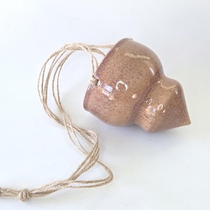 May include: A small, brown ceramic hanging planter with a natural jute twine cord. The planter has a unique, organic shape and a glossy finish. Perfect for small succulents or air plants.