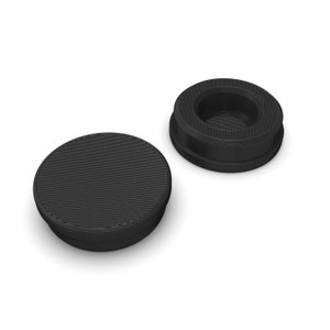 May include: Two black plastic round furniture feet with a textured surface. One foot has a recessed centre.