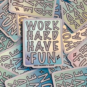 May include: A holographic sticker with the text "WORK HARD HAVE FUN" in a white outline on a rainbow background. The sticker has the artist's name and year, "NIKKI MURRAY * 2023", at the bottom.