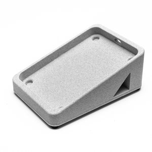May include: A gray plastic stand with a rectangular base and a sloped top. The stand has two holes on the top and a triangular cutout on the side.