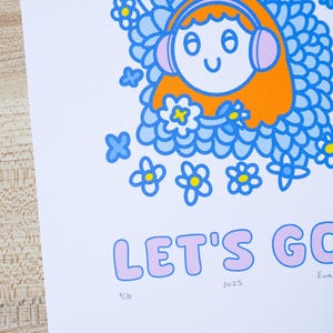 May include: A colorful art print featuring a cartoon character with orange hair and pink headphones surrounded by blue flowers. The text "LET'S GO" is in pink bubble letters. The print includes the numbers "2025" and "1/20".