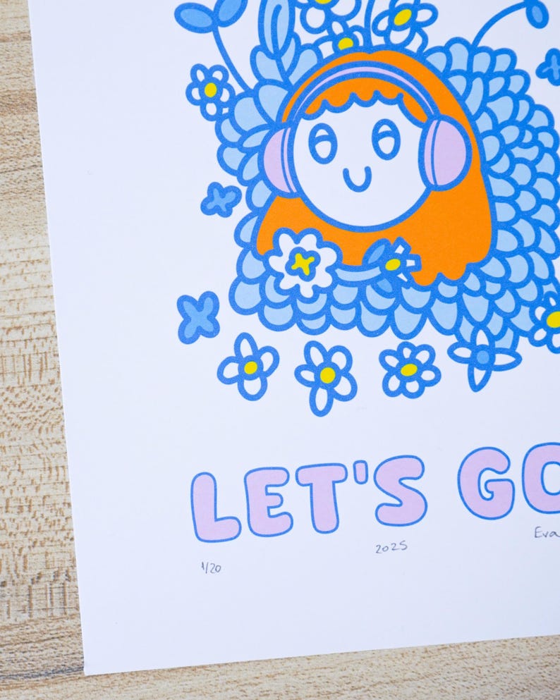 May include: A colorful art print featuring a cartoon character with orange hair and pink headphones surrounded by blue flowers. The text "LET'S GO" is in pink bubble letters. The print includes the numbers "2025" and "1/20".