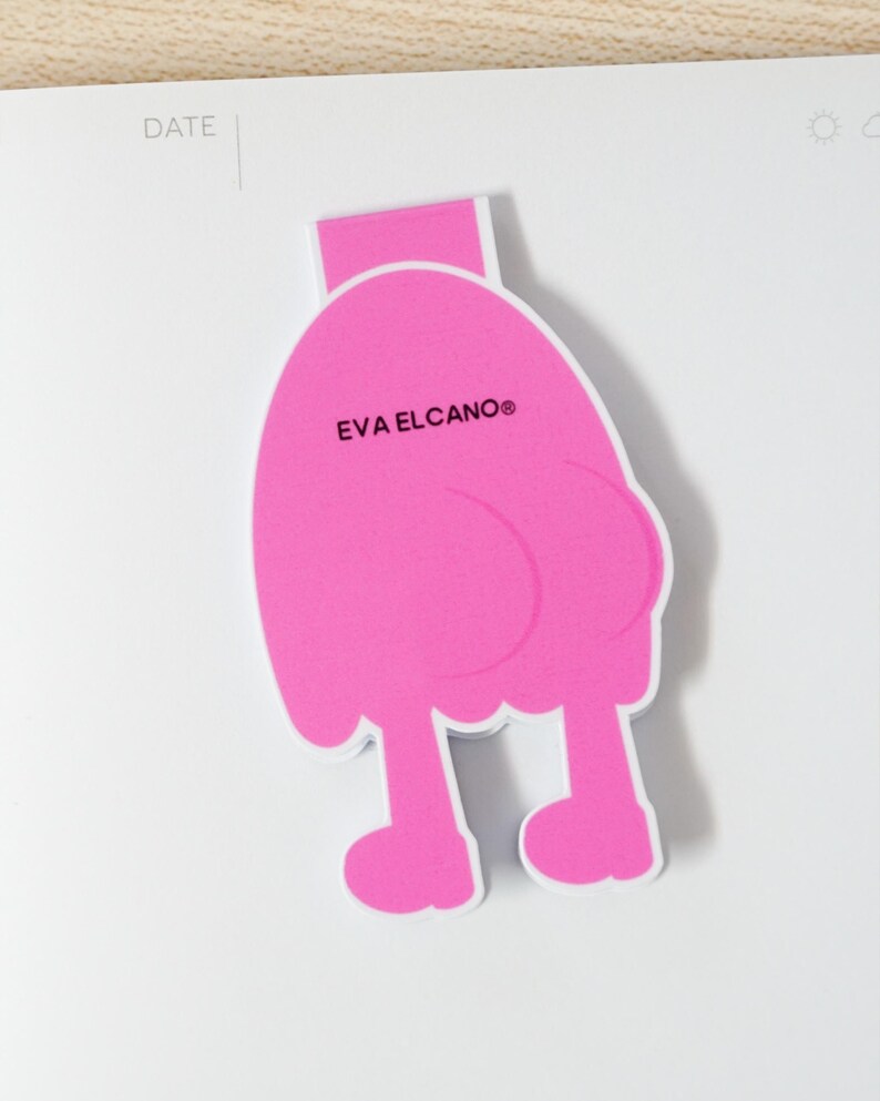 K&ouml;nnte beinhalten: Ein leuchtend pinkfarbener Lesezeichen in Form einer Cartoonfigur mit Beinen und rundem K&ouml;rper. Der Text "EVA ELCANO&reg;" ist auf dem K&ouml;rper aufgedruckt. Das Lesezeichen befindet sich auf wei&szlig;em Hintergrund.