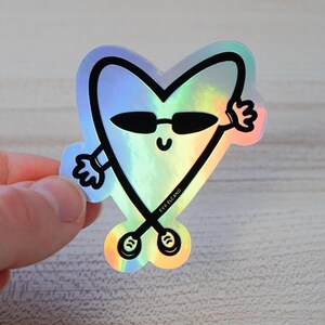 Puede incluir: Pegatina hologr&aacute;fica en forma de coraz&oacute;n con una cara sonriente que lleva gafas de sol y brazos que saludan. La pegatina tiene contornos negros y el texto "EVA ELCANO".