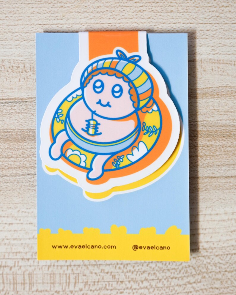 May include: A whimsical sticker featuring a cartoon character in a yellow and blue striped hat and inner tube. The character is surrounded by a yellow and orange floral design, set against a light blue background. The sticker has the website address www.evaelcano.com and the Instagram handle @evaelcano.