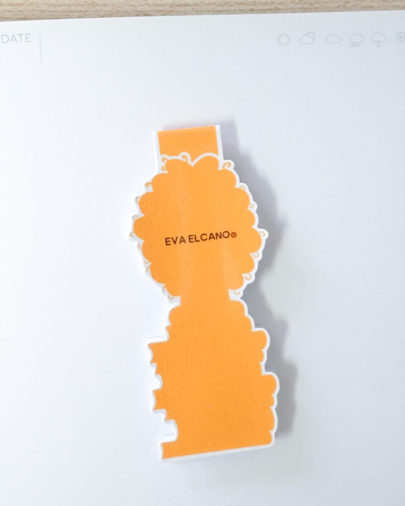 Op de afbeelding: Een oranje gestanste sticker met de tekst "EVA ELCANO" in een schreefloos lettertype. De sticker heeft een unieke vorm met een rechthoekige bovenkant en een gestileerde, wolkvormige onderkant. De sticker ligt op een wit oppervlak.