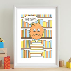 May include: A framed cartoon print featuring a whimsical orange character standing on a stack of books in front of a bookshelf. The character has a speech bubble with text in Spanish. The print has a white border and is displayed on a light-colored surface.