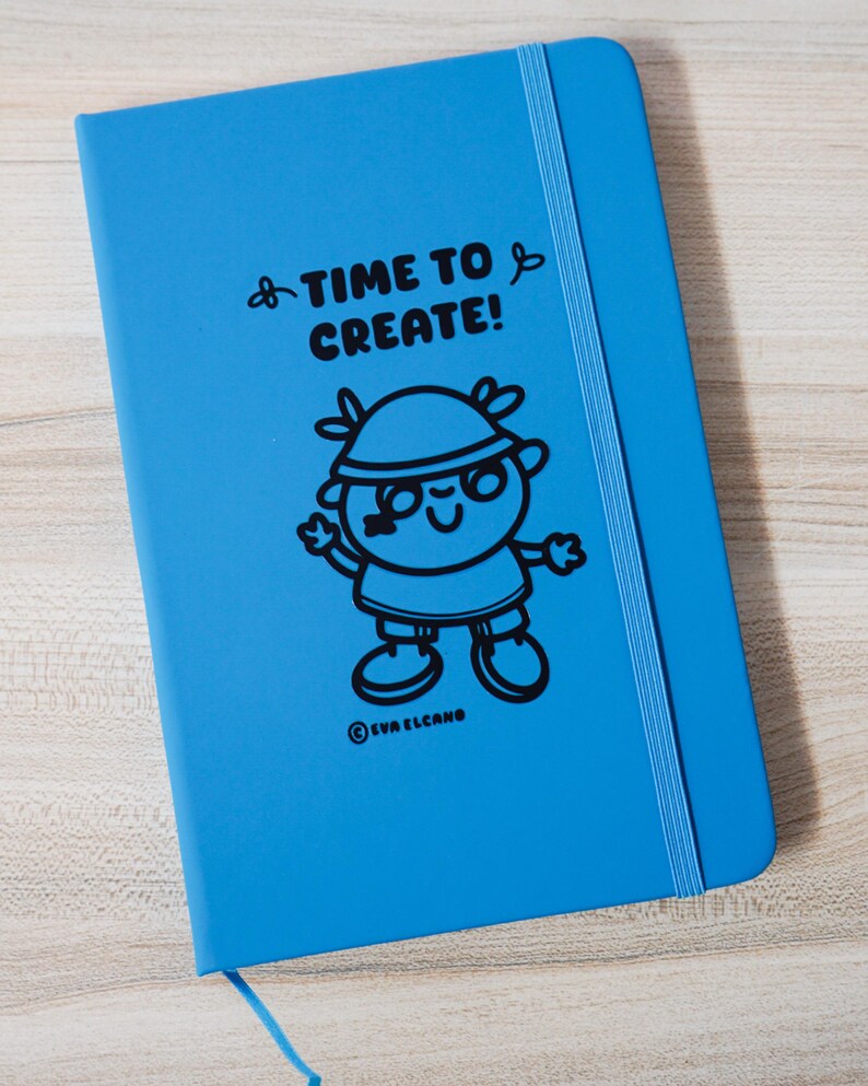May include: A vibrant blue notebook featuring the words "TIME TO CREATE!" and a black cartoon character. It has a blue elastic band and a ribbon bookmark. The brand name "EVA ELCANO" is printed at the bottom. The notebook is designed for creative use.