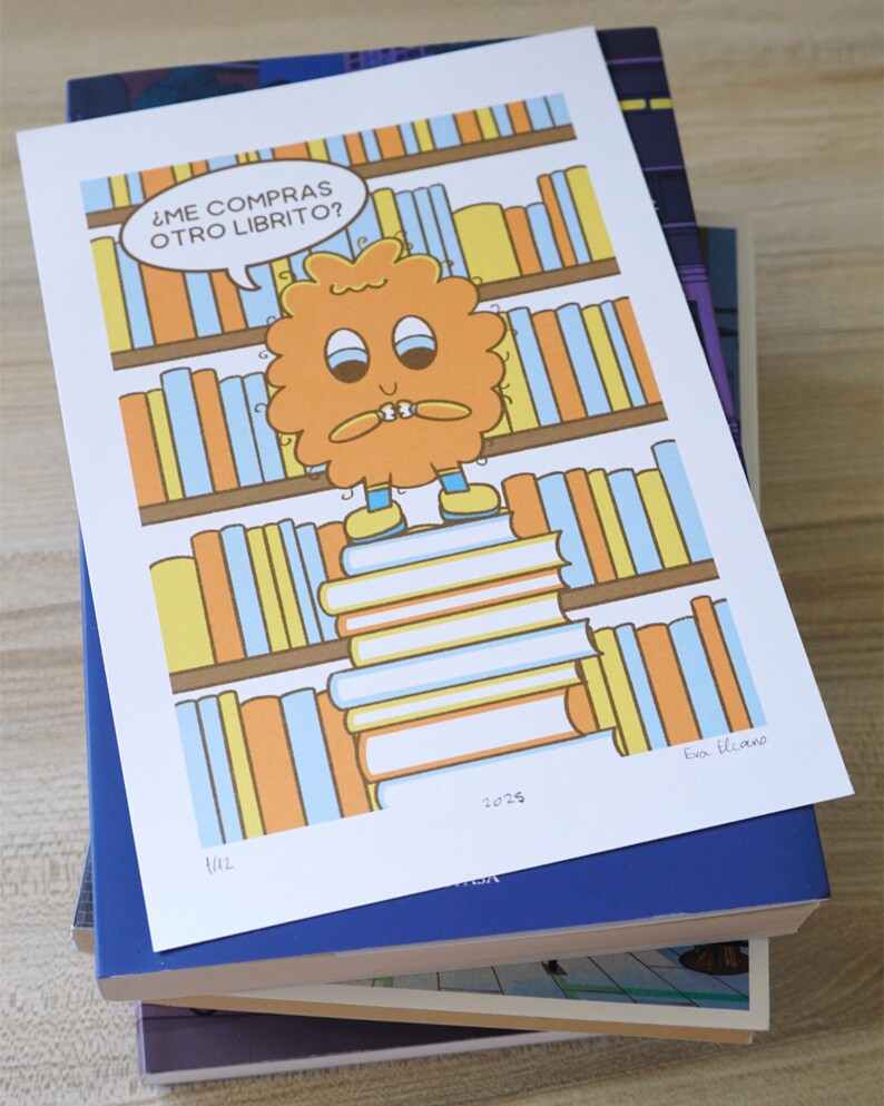 May include: A colorful illustration featuring a cartoon character standing on a stack of books, with a bookshelf background. The character has an orange, fluffy appearance and a speech bubble that says, "&iquest;ME COMPRAS OTRO LIBRITO?" The print is on top of a stack of books.