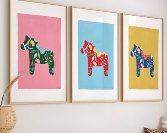Könnte beinhalten: Drei gerahmte Drucke von bunten, gemusterten, stilisierten Pferden. Die Drucke sind in rosa, blauen und gelben Rahmen und zeigen jeweils ein grünes, rotes und blaues Pferd.