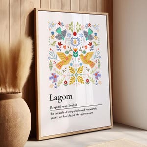 Può includere: Stampa artistica incorniciata con un colorato motivo floreale e di uccelli. La stampa include la parola "Lagom" con la sua pronuncia e definizione: "il principio di vivere una vita equilibrata, moderatamente ritmata, senza problemi; la giusta quantità."