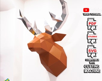 May include: A papercraft deer head model with silver antlers and a brown body. The model is mounted on a white wall. The image includes text that says "VIDEO TUTORIAL", "PDF", "STUDIO3", "SVG", "COMPATIBLE WITH CUTTING MACHINE", and "3dfancy".