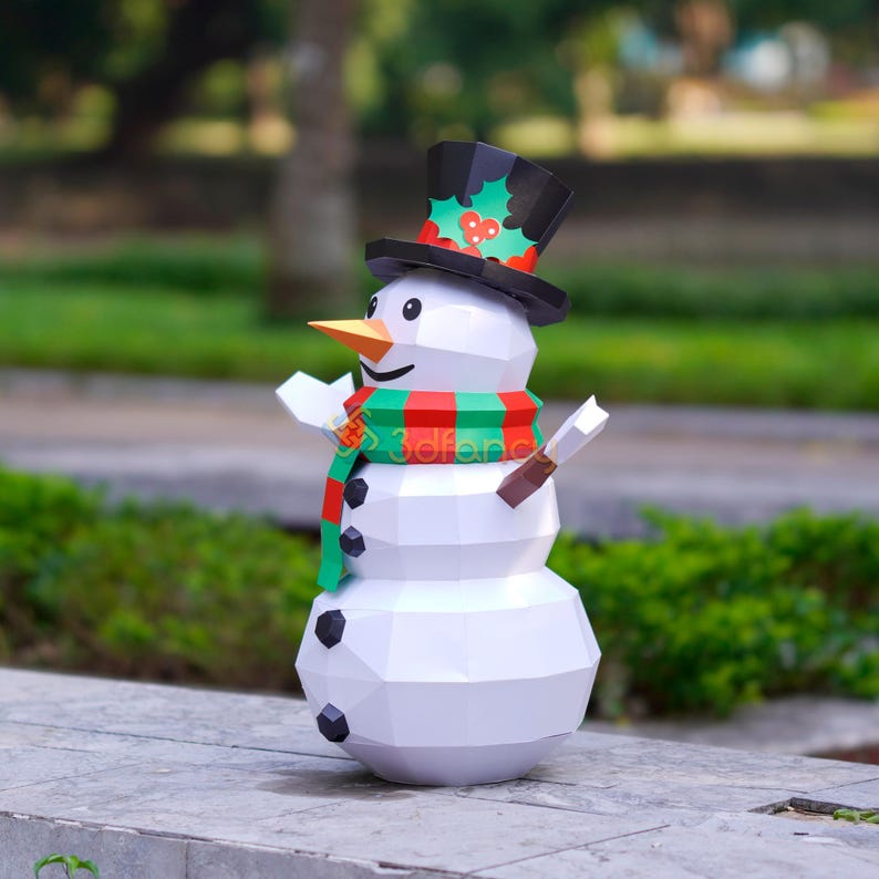 May include: A white, geometric snowman figure with a black top hat adorned with holly. It has an orange carrot nose, black button eyes, and a red and green scarf. The snowman has stick arms and black coal buttons.