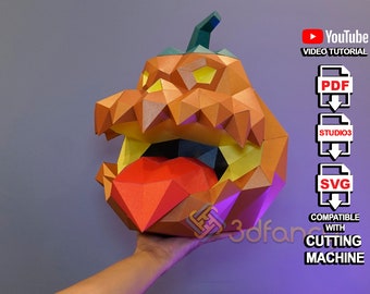 May include: A 3D papercraft model of a pumpkin with a wide open mouth and a red tongue sticking out. The model is made of orange, yellow, and red paper and is compatible with cutting machines. The image includes the text "PDF", "STUDIO3", "SVG", "COMPATIBLE WITH CUTTING MACHINE", and "YouTube VIDEO TUTORIAL".
