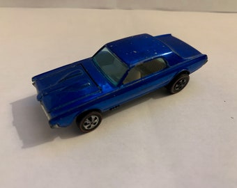 Può includere: Un modello di auto giocattolo in metallo blu di una Ford Mustang del 1967.