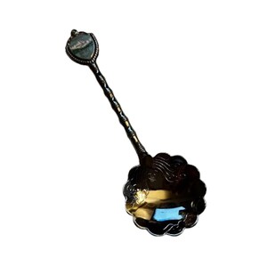 May include: A decorative spoon with a detailed design. The spoon features a floral-shaped bowl and a twisted handle. The handle is topped with a small, shield-shaped embellishment with a landscape scene. The spoon is made of a metallic material with a dark finish.