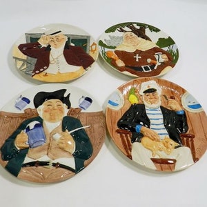 May include: Set of four decorative ceramic plates featuring colorful illustrations of men in various poses. Each plate depicts a different character, including a man with a telescope, a man with a pipe, a man with a mug, and a man with a parrot.