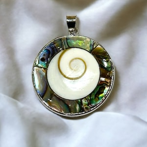 Peut inclure: Un pendentif en argent avec une incrustation ronde de nacre d'ormeau. La coquille présente un motif en spirale dans des tons de vert, bleu et blanc.