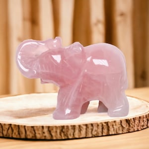 Peut inclure: Une figurine d'éléphant en quartz rose. L'éléphant est sculpté dans une seule pièce de quartz rose et a une finition lisse et polie.