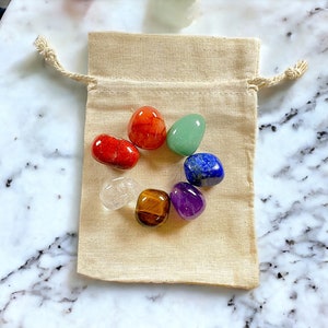 Peut inclure: Un ensemble de sept pierres de chakra dans un petit sac à cordon beige. Les pierres sont disposées en cercle et sont rouge, orange, jaune, vert, bleu, indigo et violet.