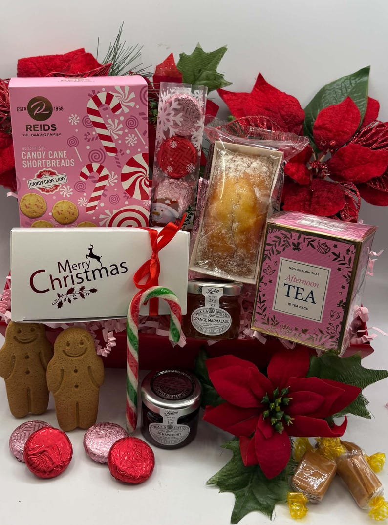 May include: A holiday gift basket containing a pink box of Reids Candy Cane Shortbreads, a white Merry Christmas box, a loaf cake, a box of Afternoon Tea, two jars of preserves, gingerbread cookies, wrapped chocolates, and a candy cane.