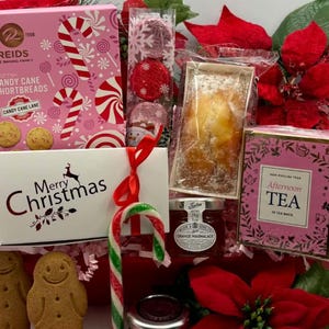 May include: A holiday gift basket containing a pink box of Reids Scottish Candy Cane Shortbreads, a white box labeled Merry Christmas, a package of red foil-wrapped chocolates, a small loaf cake, orange marmalade, and Afternoon Tea.