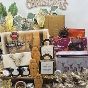 May include: A Christmas gift basket containing a box of Highland Speciality Scottish Shortbread Assortment, a box of Festive Luxury Christmas Puddings, a tin of tea, jars of jam, gingerbread men, Rosie & Roni's Fudge, and nuts.