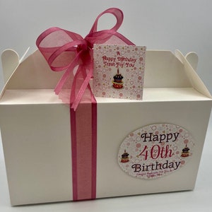 Puede incluir: Una caja de regalo blanca con una cinta rosa y una etiqueta rosa que dice "A Happy Birthday Treat For You". La caja tambi&eacute;n tiene una pegatina rosa y blanca que dice "Happy 40th Birthday Created Especially For You".