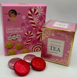 May include: A pink box of Reids Scottish Candy Cane Shortbreads featuring candy cane graphics and four round cookies, alongside a pink and gold box of New English Teas Afternoon Tea containing 10 tea bags, with two red and two pink foil-wrapped chocolates.