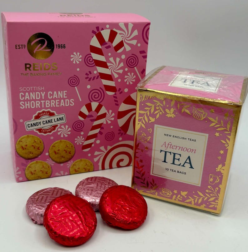 May include: A pink box of Reids Scottish Candy Cane Shortbreads featuring candy cane graphics and four round cookies, alongside a pink and gold box of New English Teas Afternoon Tea containing 10 tea bags, with two red and two pink foil-wrapped chocolates.