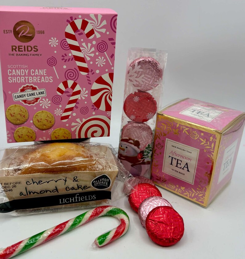 May include: A collection of holiday treats including a pink box of Reids Scottish Candy Cane Shortbreads, a clear tube of red and pink foil-wrapped chocolates, a box of New English Tea Afternoon Tea, and a Lichfields cherry and almond cake.