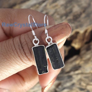 May include: Black tourmaline gemstone earrings with silver hooks. The rectangular stones are set in silver.