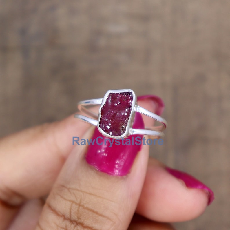 Peut inclure: Bague en argent avec une pierre pr&eacute;cieuse brute de forme rectangulaire, de couleur rouge fonc&eacute;. Le rubis est serti dans un sertissage &agrave; lunette. La bague a un design &agrave; tige fendue.