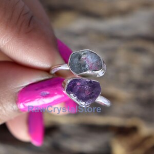 May include: Two silver rings with raw amethyst and aquamarine gemstones. The rings are stacked on top of each other. The amethyst is a deep purple color and the aquamarine is a light blue color.