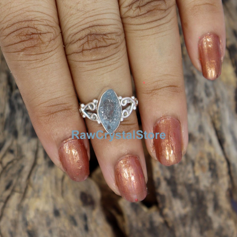 May include: A silver ring featuring a light blue aquamarine gemstone. The ring has a delicate, ornate design.