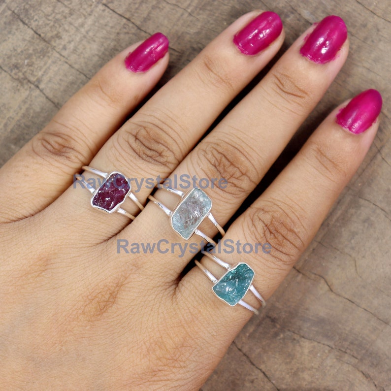 Peut inclure: Trois bagues en argent, chacune orn&eacute;e d'une pierre brute rectangulaire de couleur rouge, bleu clair et turquoise. Les bagues ont un design &agrave; double anneau. L'image est sur un fond neutre.