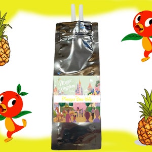 Könnte beinhalten: Ein silberner Beutel mit einem Strohhalm, der aus der Oberseite herausragt. Der Beutel hat ein Etikett mit der Aufschrift "Magic Kingdom" und "Pineapple Dole Whip". Das Etikett zeigt auch ein Cartoon-Bild von Cinderellas Schloss und anderen Disney-Charakteren. Im Hintergrund befinden sich zwei Cartoon-Ananas und ein Cartoon-Vogel.