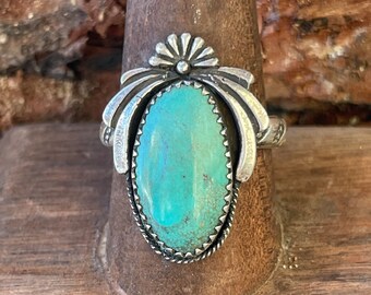 May include: A silver ring with a turquoise stone set in a floral design.