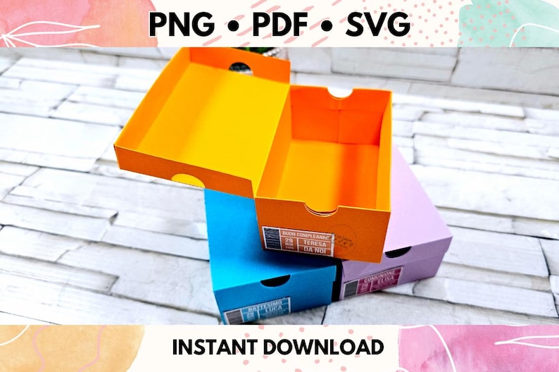 May include: Three colorful boxes with lids, stacked on top of each other. The top box is orange, the middle box is blue, and the bottom box is purple. The boxes have text on them, including "Super Extra Grande" and "Teresa Dani".