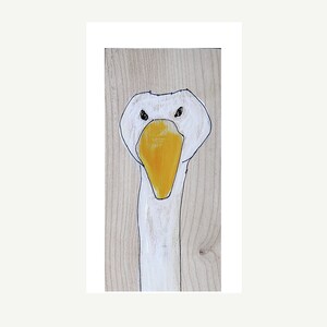 May include: A white goose with a yellow beak painted on a wood panel.