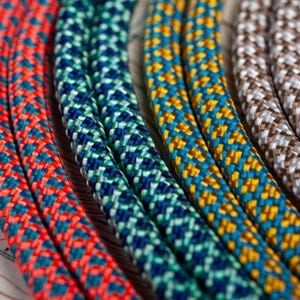 May include: Close-up of four colorful braided ropes with different patterns. The ropes are red, blue, yellow, and gray.