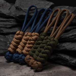 Puede incluir: Tres tiradores de cremallera de paracord con nudos trenzados complejos. Un tirador es azul marino, otro es color canela y otro es verde oliva. Cada tirador incluye un lazo de cuerda para su fijaci&oacute;n con un dise&ntilde;o trenzado denso.