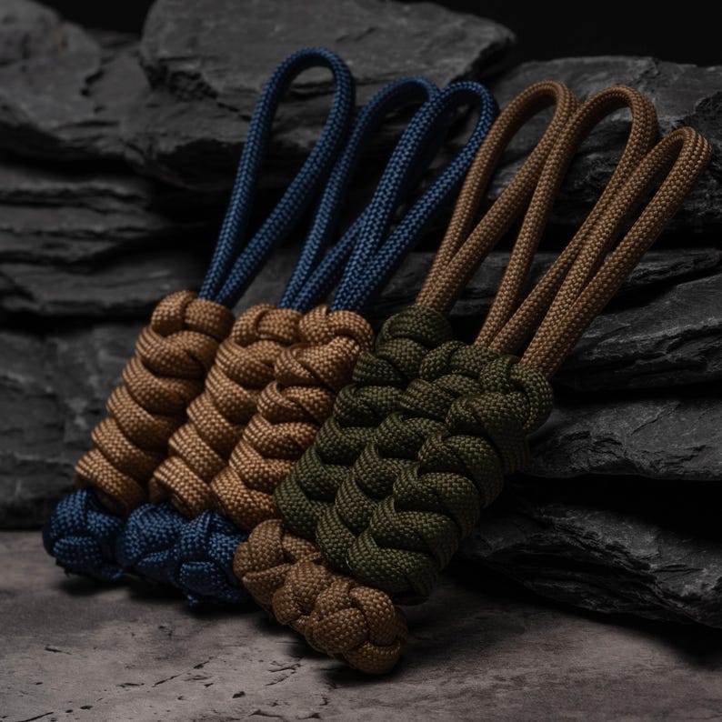 Puede incluir: Tres tiradores de cremallera de paracord con nudos trenzados complejos. Un tirador es azul marino, otro es color canela y otro es verde oliva. Cada tirador incluye un lazo de cuerda para su fijaci&oacute;n con un dise&ntilde;o trenzado denso.