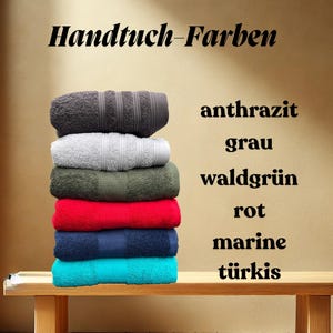 May include: A stack of towels in various colors, including gray, green, red, blue, and turquoise. The towels are labeled with the German words for each color: anthrazit, grau, waldgr&uuml;n, rot, marine, and t&uuml;rkis.