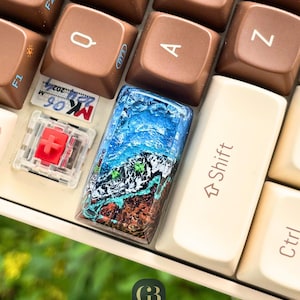 May include: A white ceramic mug with a black handle and the text "But First, Coffee" in a bold, black font. The mug is set against a neutral background, highlighting its simple design.